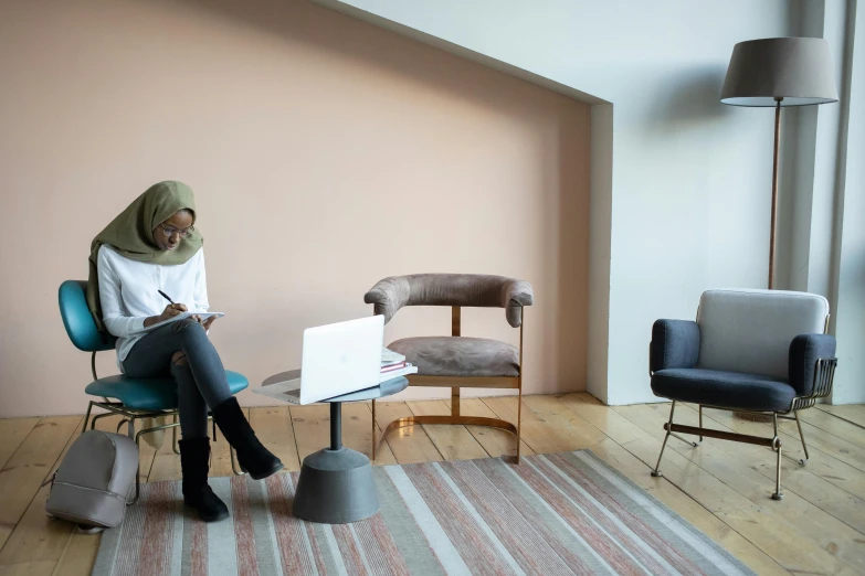 a woman sitting in a chair with a laptop, inspired by Afewerk Tekle, trending on unsplash, in a open-space working space, dezeen showroom, muted pastels, tehran