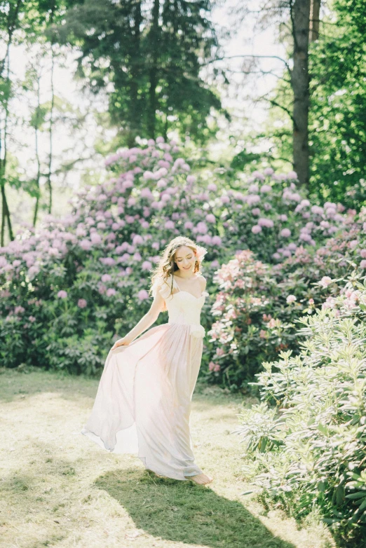 a woman standing on top of a lush green field, inspired by Oleg Oprisco, unsplash, romanticism, lilacs, wearing a wedding dress, sparkling in the sunlight, in serene forest setting