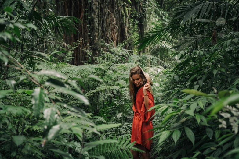 a woman standing in the middle of a forest, by Daniel Lieske, sumatraism, orange robe, tropical plants, avatar image, lifestyle