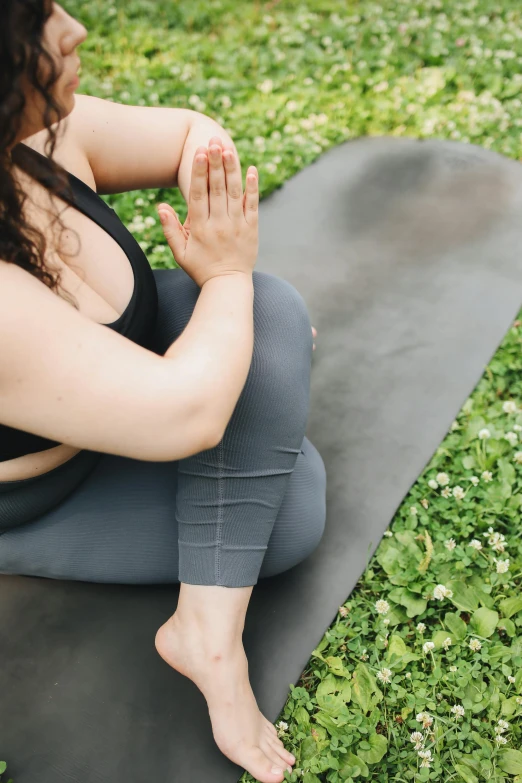 a woman sitting on a yoga mat in the grass, trending on pexels, renaissance, an overweight, in a fighting pose, grey, full frame image