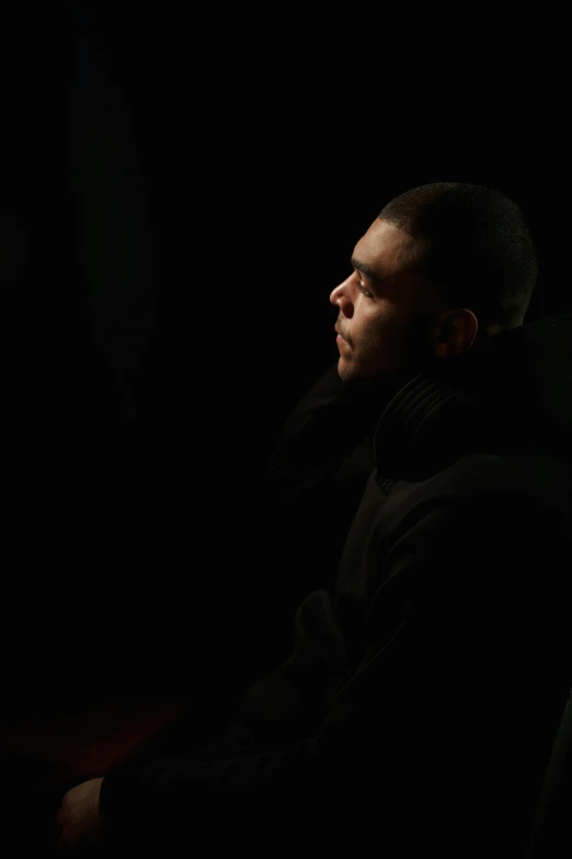 a man sitting in a chair in the dark, brazilian ronaldo, ((portrait)), drake, left profile