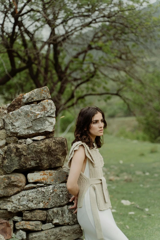 a woman standing in front of a stone wall, ana de armas, pastoral, digital still, feature