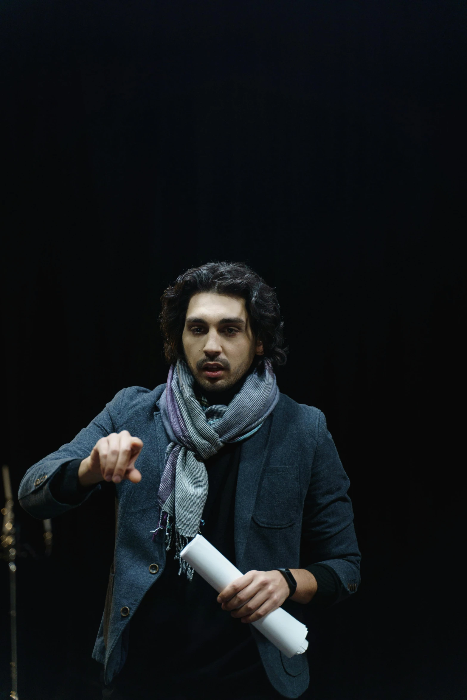 a man standing next to a microphone on a stage, by Youssef Howayek, [ theatrical ], mahira khan as a d&d wizard, on a gray background, conductor