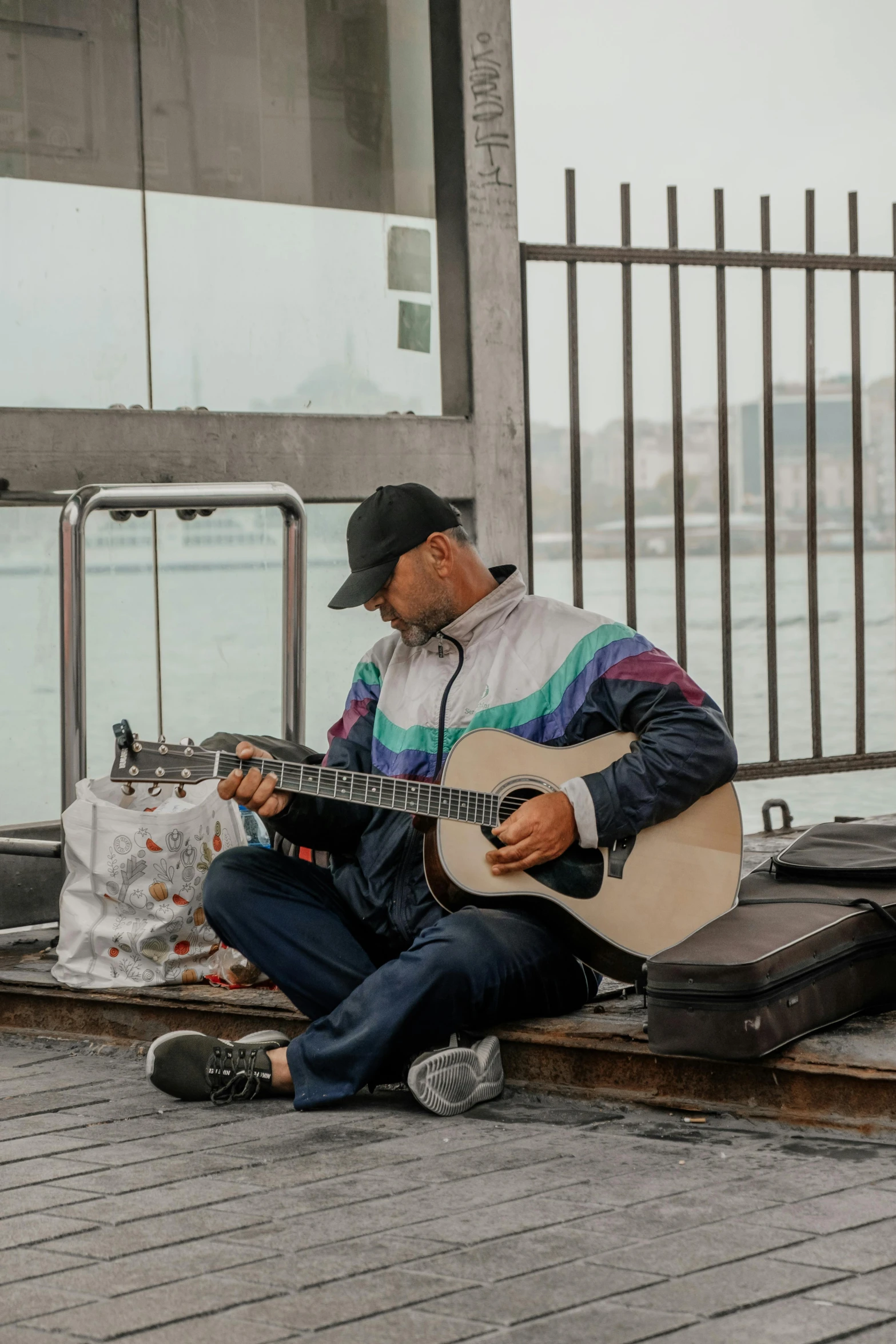 a man sitting on the ground playing a guitar