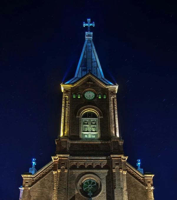 a tall clock tower lit up at night, by Adam Marczyński, romanesque, faroe, blue, high detail photograph, brown