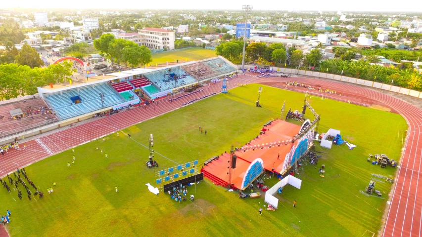 a group of people standing on top of a lush green field, an aerial tennis court, carnaval de barranquilla, sun down, profile image