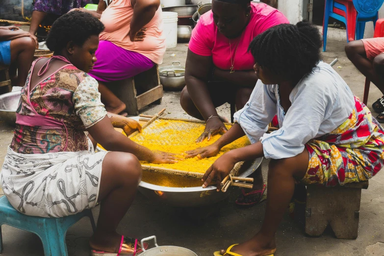 a group of women sitting around a bowl of food, by Ingrida Kadaka, trending on unsplash, favela honeybee hive, cooking oil, with yellow cloths, avatar image