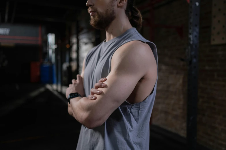 a man standing in a gym with his arms crossed, by Adam Marczyński, pexels contest winner, realism, angular jawline, background image, athletic crossfit build, close up shot from the side