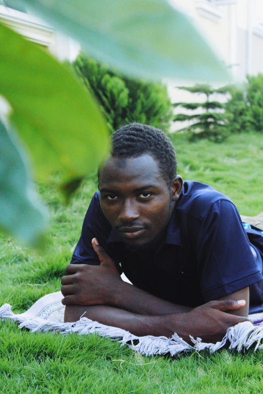 a man laying on a blanket in the grass, inspired by Ibram Lassaw, happening, adut akech, lovingly looking at camera, profile image, professional picture