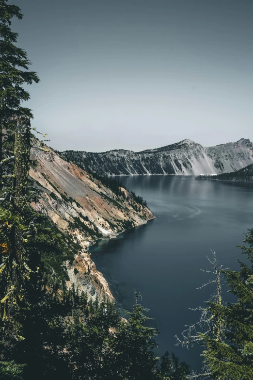 a large body of water surrounded by trees, pexels contest winner, crater, steep cliffs, grey, 2 0 0 0's photo