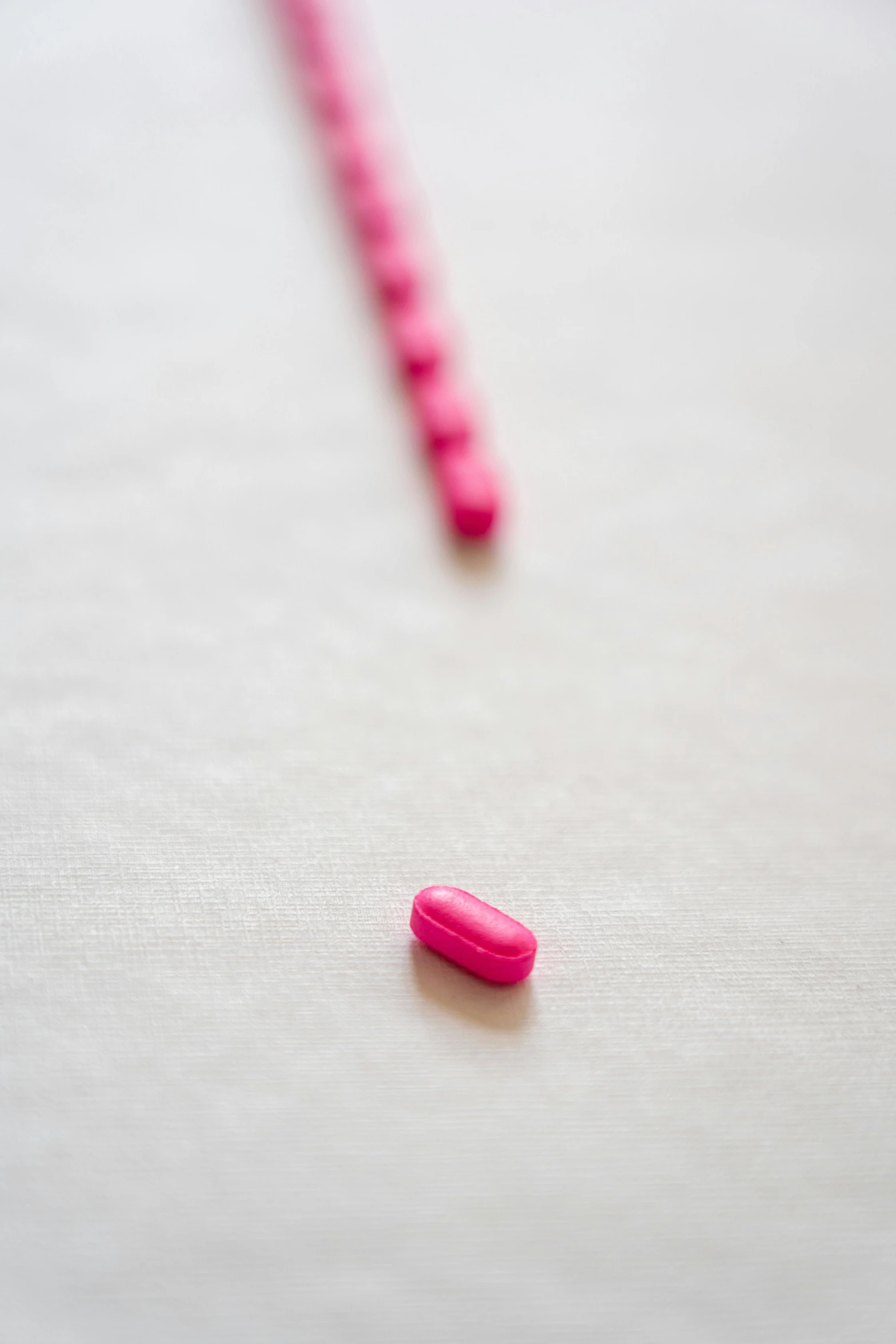 a pink pill sitting on top of a table, unsplash, very elongated lines, in a row, yet unrecognizable, adafruit