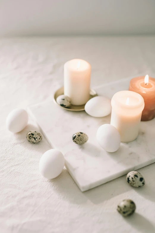 a couple of candles sitting on top of a table, a marble sculpture, trending on pexels, eggs, square, white, indoor picture