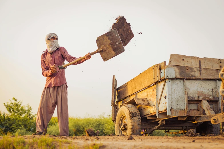 a man holding a shovel next to a dump truck, inspired by Steve McCurry, pexels contest winner, villagers busy farming, islamic, avatar image, dirt stains