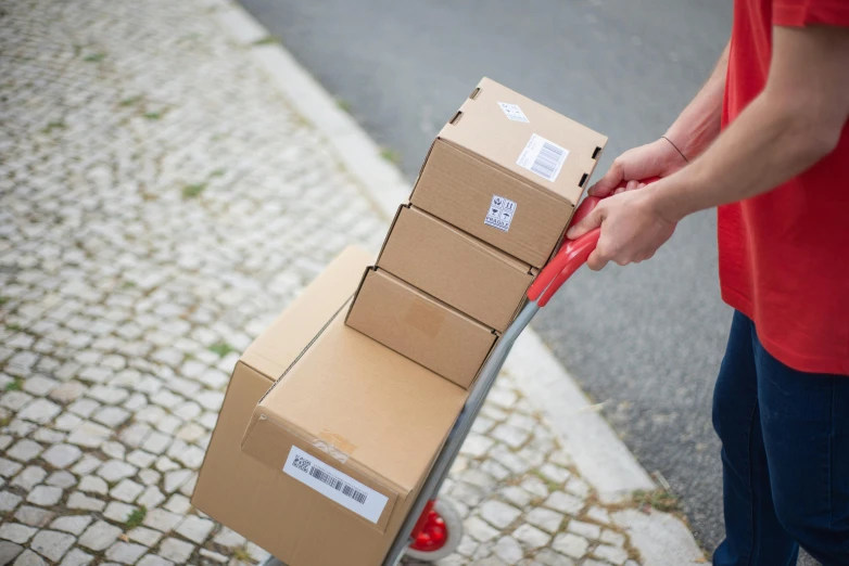 a person pushing a cart with boxes on it, by Matthias Stom, pexels contest winner, packaging design, close up angle, multi-part, delivering parsel box