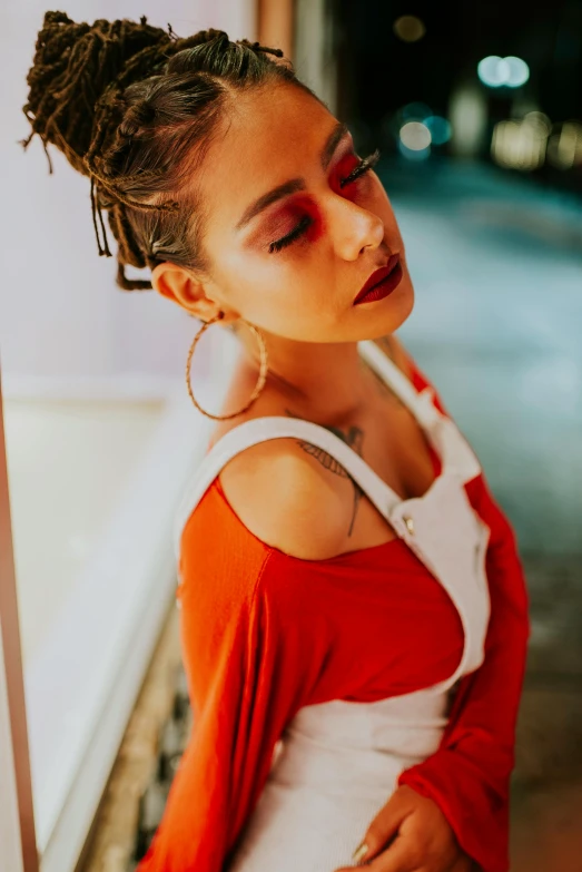 a woman in a red and white dress leaning against a wall, an album cover, inspired by Elsa Bleda, trending on pexels, antipodeans, mixed race woman, ((red)) baggy eyes, with tattoos, sunset view