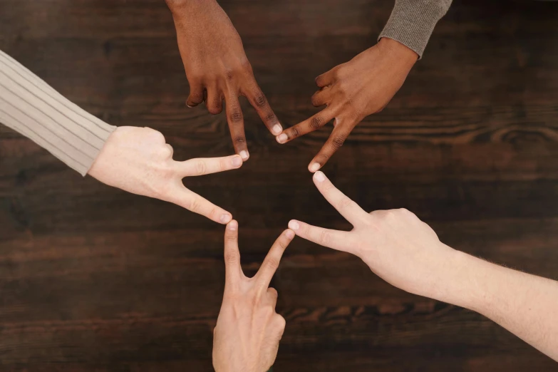 a group of people making a star with their hands, by Nina Hamnett, trending on pexels, panel of black, peace sign, hand on table, brown