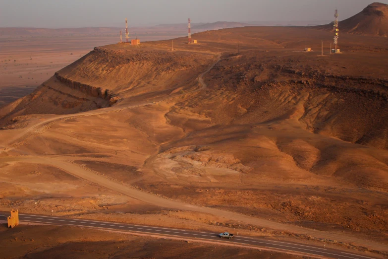 a car driving down a dirt road in the desert, by Breyten Breytenbach, pexels contest winner, les nabis, oil rig, view from high, egyptian setting, “ aerial view of a mountain