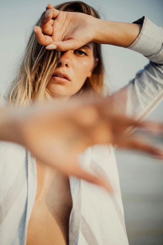 a woman making a stop sign with her hands, unsplash, happening, photoshoot for skincare brand, looking off into the distance, coastal, blurred detail