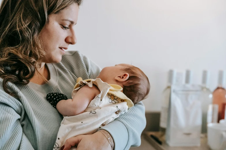 a woman holding a baby in her arms, a photo, pexels, charli bowater and artgeem, profile image, rectangle, lachlan bailey