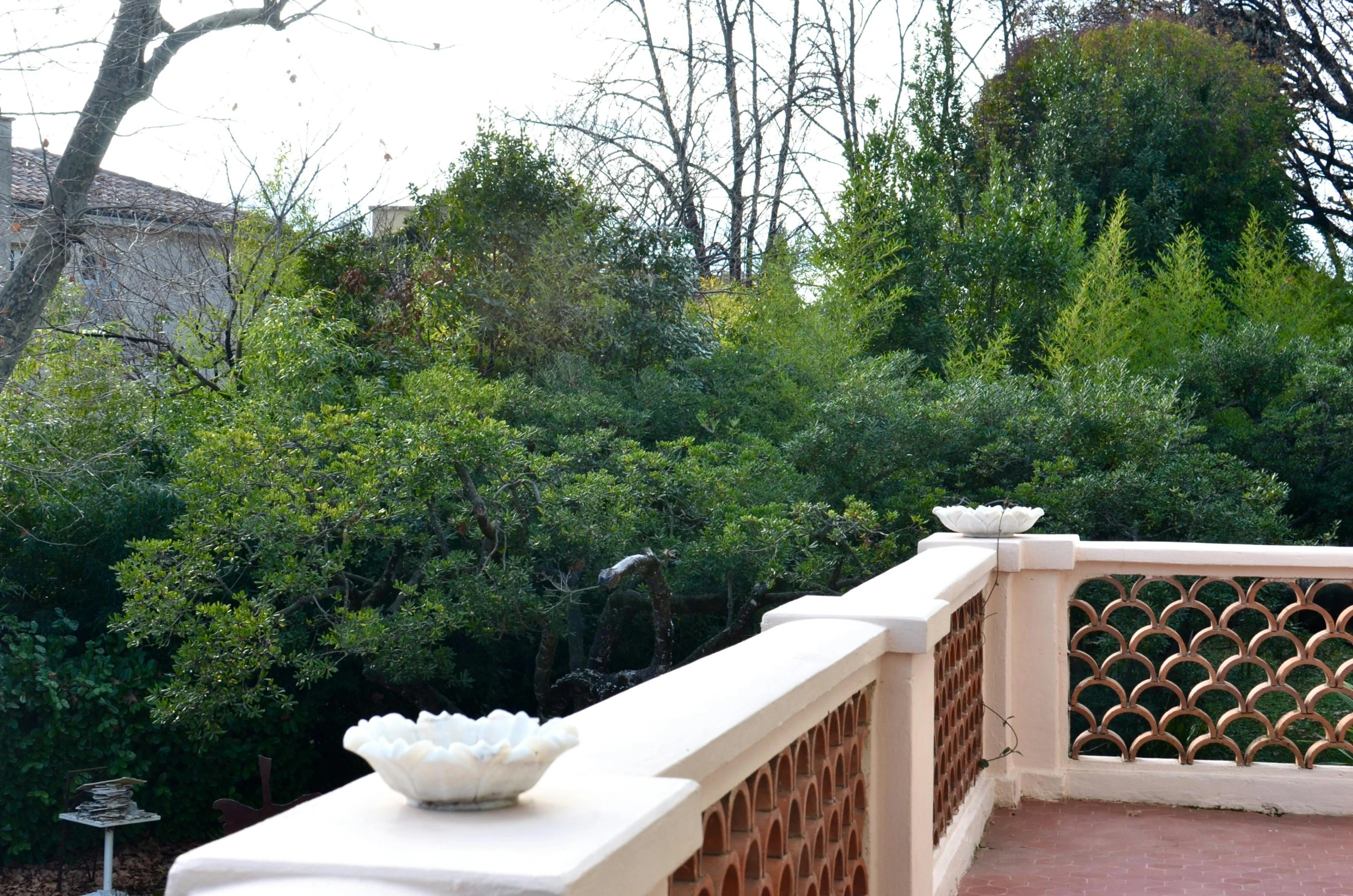 a white vase sitting on top of a balcony, arabesque, trees outside, botanic garden, sol retreat, railing