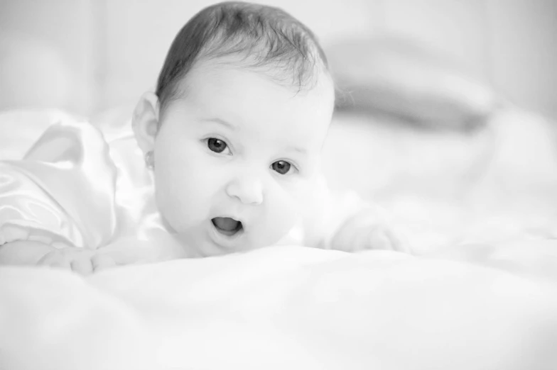 a black and white photo of a baby on a bed, by John Hutton, pexels, surprised, highkey, hd footage, soft lulling tongue