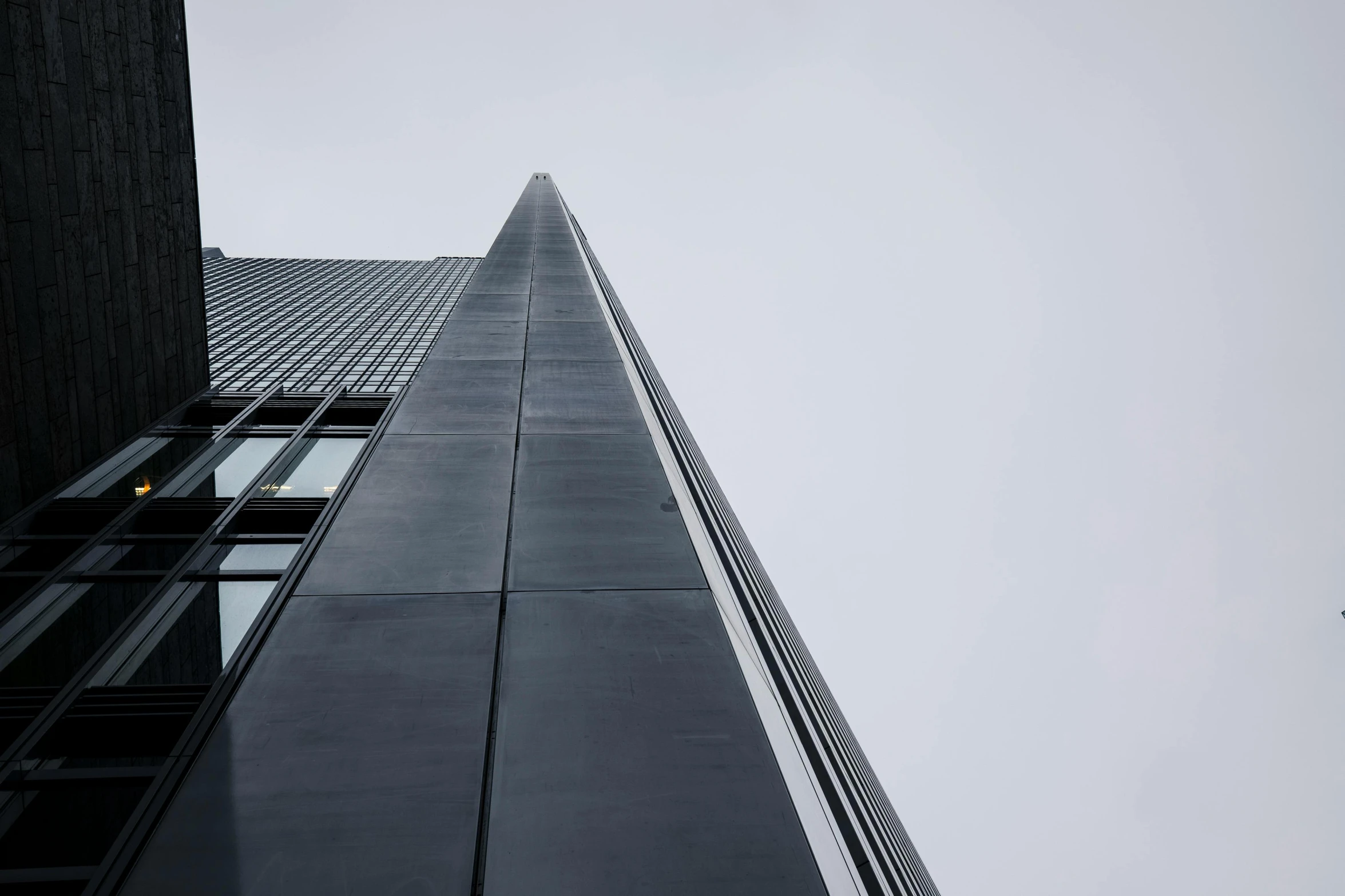 a plane flying in front of a tall building, an album cover, inspired by Tadao Ando, pexels contest winner, minimalism, grey sky, iron cladding, view from the side”, herzog de meuron