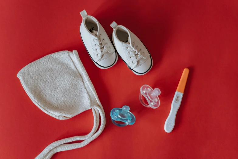 a pair of white shoes sitting on top of a red surface, pexels contest winner, small vials and pouches on belt, fetus, toys, profile pic