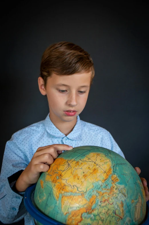 a young boy holding a globe in his hands, a colorized photo, trending on unsplash, well-groomed model, studious, greta thunberg, product introduction photo