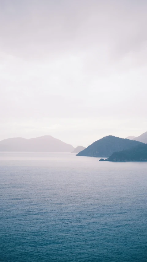 a large body of water with mountains in the background, an album cover, trending on unsplash, minimalism, mediterranean island scenery, faded color film, 4 k cinematic photo, many islands