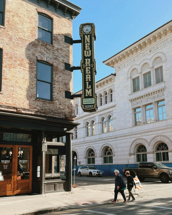 a couple of people walking down a street, by Dan Frazier, trending on unsplash, art nouveau, old signs, brick building, epic theater, high quality photo