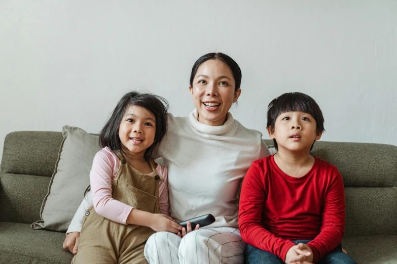 a woman and two children sitting on a couch, pexels, mingei, avatar image, an asian woman, tv, high quality upload