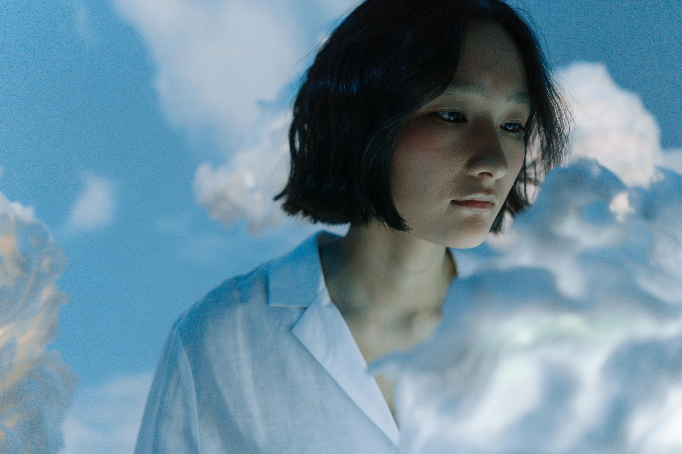 a woman standing in front of a cloudy sky, an album cover, inspired by Fei Danxu, unsplash, japan. volumetric lighting, androgynous person, still from a live action movie, teamlab