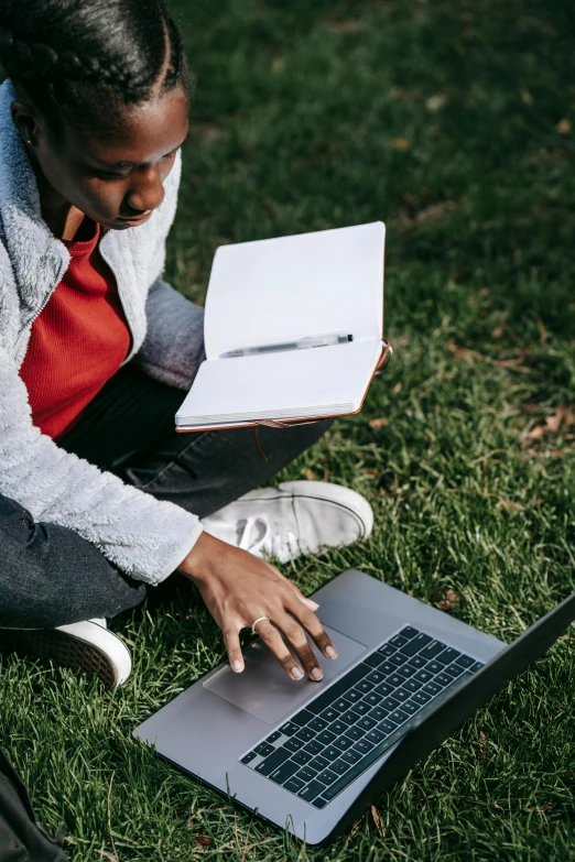 a woman sitting on the grass using a laptop, pexels, happening, black teenage boy, holding notebook, professional grade, looking at the ground