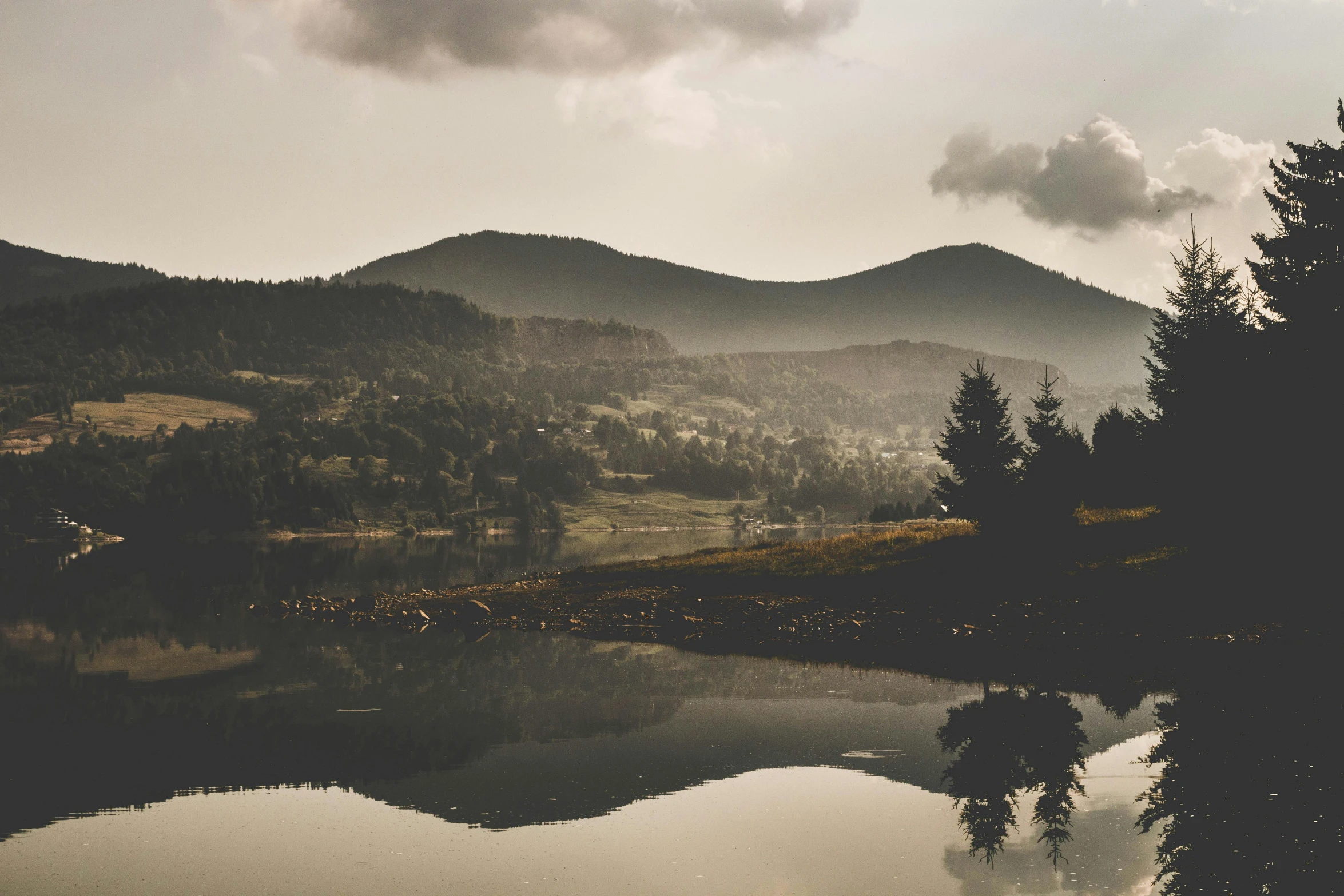 a body of water with a mountain in the background, by Adam Szentpétery, pexels contest winner, romanticism, rolling foothills, mirror reflections, faded effect, overlooking a valley with trees