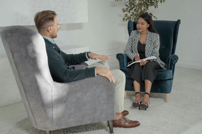 a woman sitting in a chair talking to a man, profile image