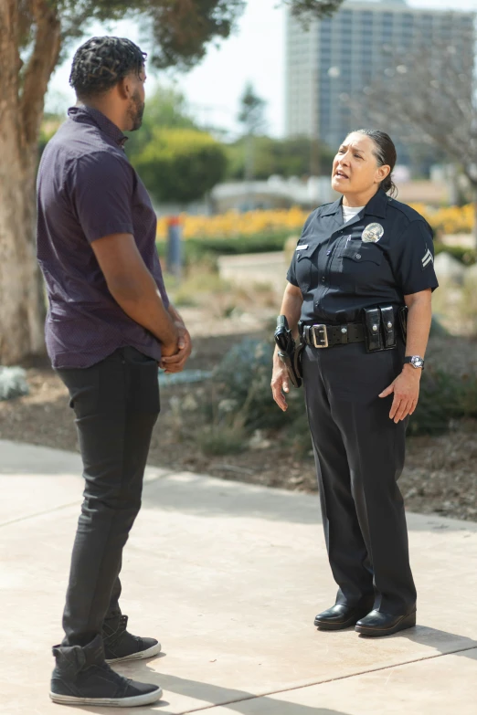 a police officer talking to a woman on a sidewalk, fan favorite, diverse, full-body-shot, blue uniform