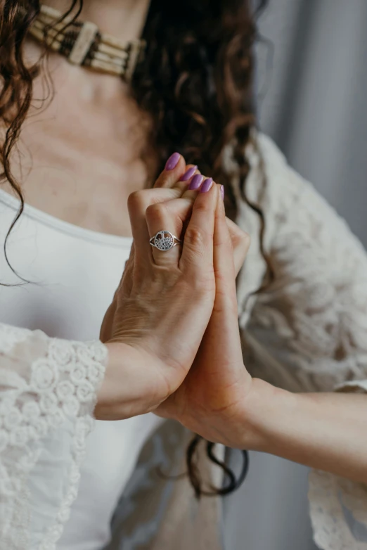 a woman in a white dress holding her hands together, silver and sapphire, supportive, holding each other, doing witchcraft