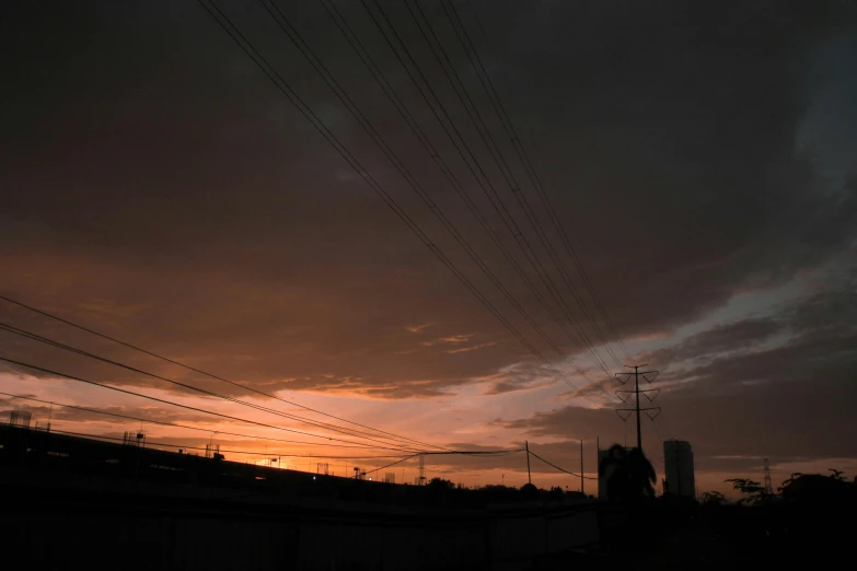 a train traveling down train tracks under a cloudy sky, a picture, pexels contest winner, realism, nuclear sunset, telephone wires, dark photo, silhouette over sunset