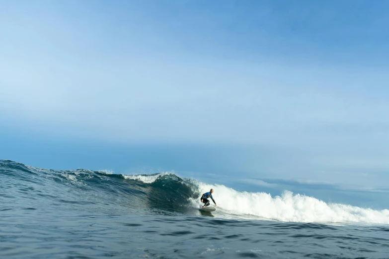 a man riding a wave on top of a surfboard, by Jessie Algie, pexels contest winner, minimalism, reefs, nordic, surfing a barrel wave, blue