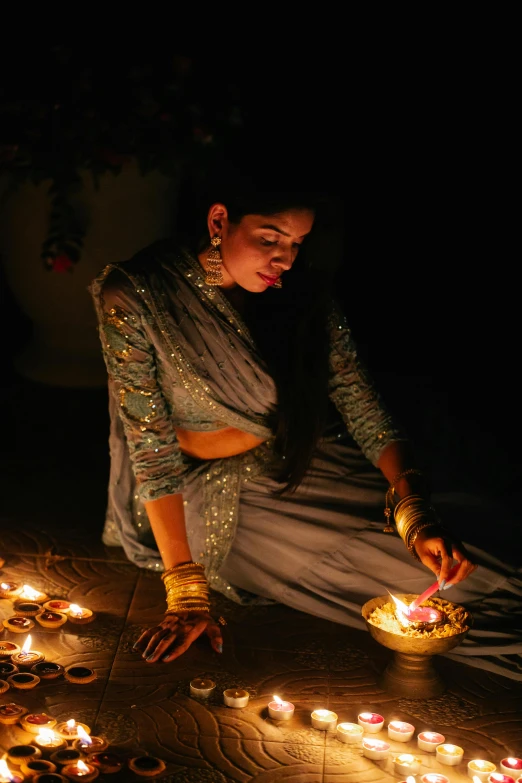 a woman sitting on the ground lighting candles, pexels contest winner, bollywood, square, arabian nights inspired, grey