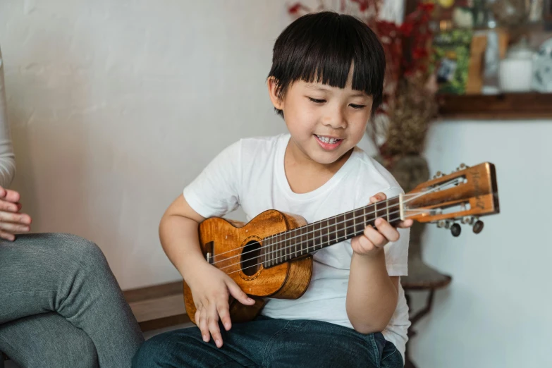 a little boy that is sitting down with a guitar, inspired by Reuben Tam, pexels contest winner, shin hanga, ukulele, asian female, holding an epée, thumbnail