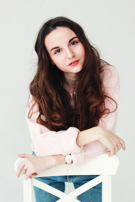 a woman sitting on top of a white chair, by Lucia Peka, shutterstock, renaissance, portrait of teen girl, pink hue, wide forehead, long wavy brown hair