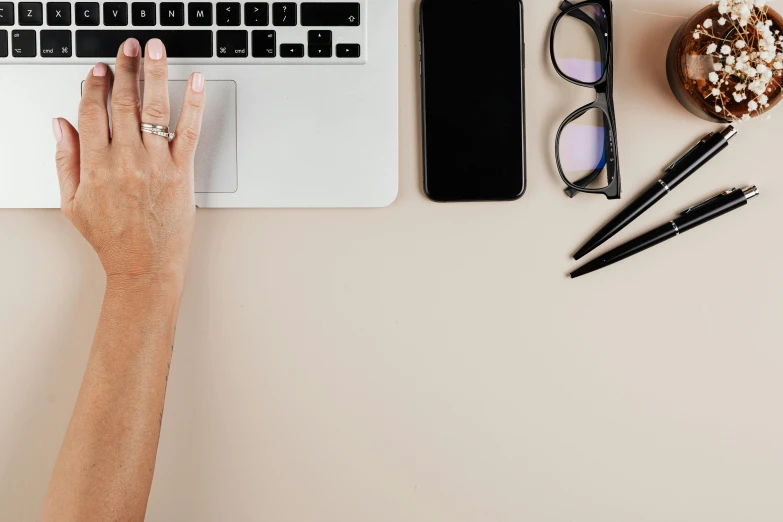 a person typing on a laptop next to a cup of coffee, trending on pexels, figuration libre, wearing black rimmed glasses, minimal pink palette, background image, ornate designs on desk