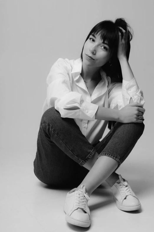 a black and white photo of a woman sitting on the ground, inspired by Miwa Komatsu, white shirt and jeans, promotional image, studio photo, rebecca sugar