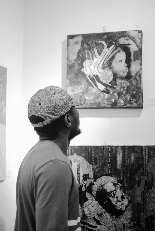 a black and white photo of a man looking at art, a black and white photo, by artist, black arts movement, trending on artststion, psychedelic hip-hop, looking from shoulder, paiting