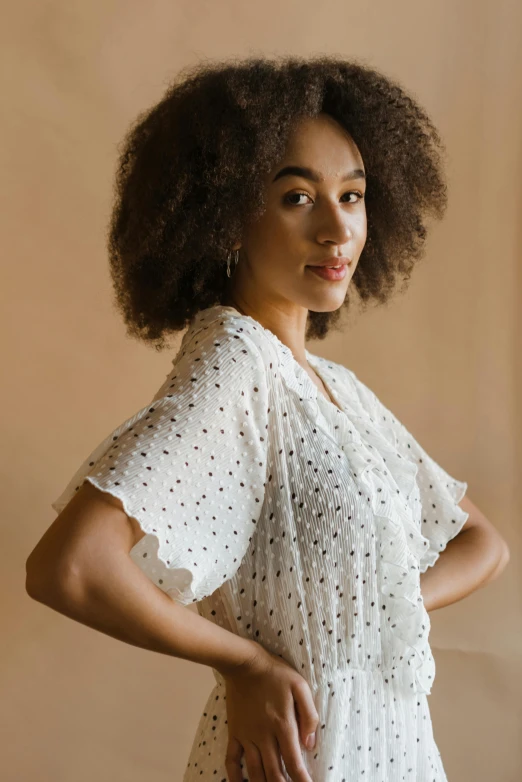 a woman standing with her hands on her hips, a portrait, trending on pexels, made of dots, curls hair, cream colored blouse, mixed race woman