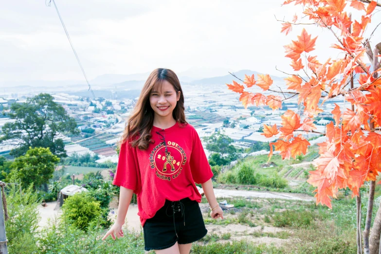 a woman standing on top of a lush green hillside, a portrait, pexels contest winner, red t-shirt, tzuyu from twice, colorful kitsune city, avatar image