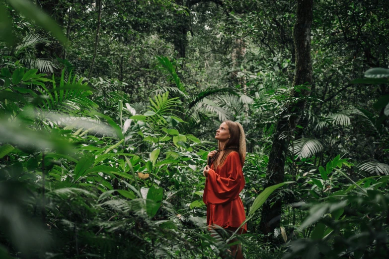 a woman standing in the middle of a forest, by Daniel Lieske, sumatraism, avatar image, wearing an orange jumpsuit, lush greenery, profile image