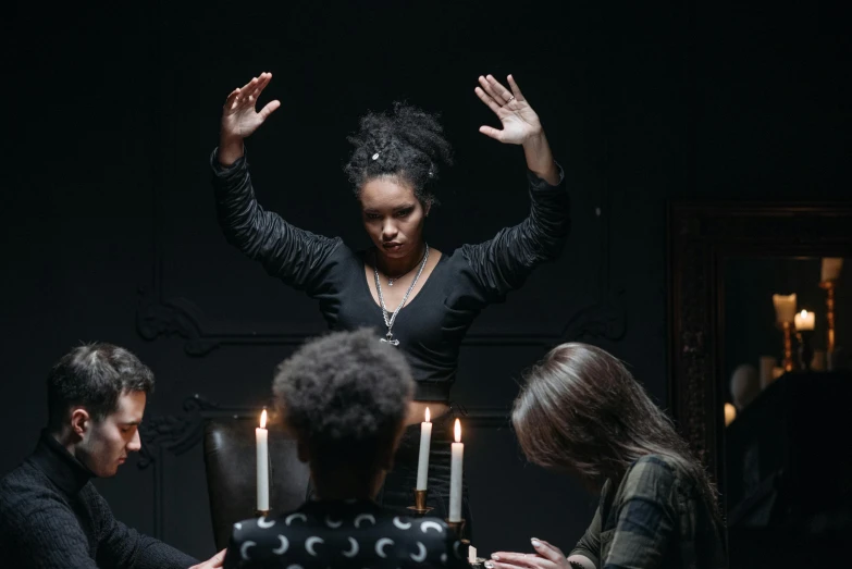 a group of people sitting around a table with candles, inspired by Carrie Mae Weems, pexels contest winner, renaissance, female mage conjuring a spell, an ahoge stands up on her head, four hands, black