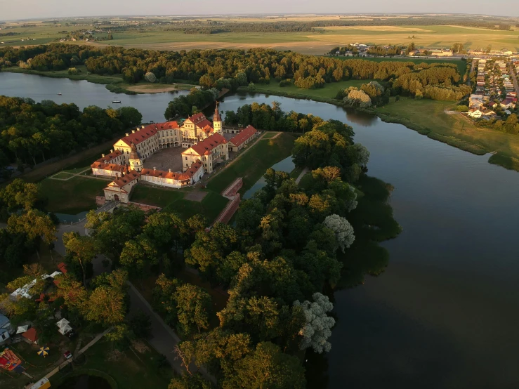 a large building sitting on top of a lush green field, by Petr Brandl, baroque, sky - high view, parks and lakes, during golden hour, zdzislaw